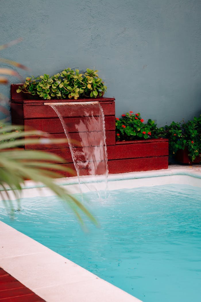 Stylish backyard pool with cascading waterfall and vibrant greenery.